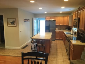 A kitchen with wooden cabinets, a refrigerator, a microwave, and a sink.
