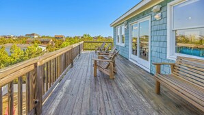 A wooden deck with outdoor seating, overlooking a residential area with houses and greenery.