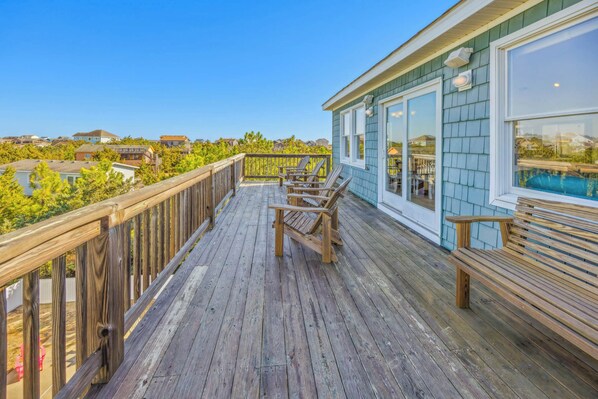 A wooden deck with outdoor seating, overlooking a residential area with houses and greenery. - Oceanview Dog Friendly w/ Private Pool, Hot Tub, Game Room, and Home Theaters (Salvo)