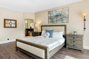 Un dormitorio con una cama grande, una mesita de noche, un aparador y una lámpara fijada a la pared.