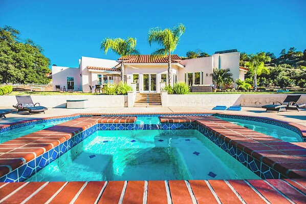 Una casa moderna con piscina, mobiliario de exterior y un jardín bien cuidado.