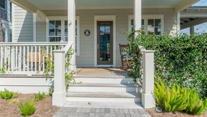 A front porch with a wooden deck, white railings, and a door with a glass panel. - Spacious, golf cart included-pet friendly, short stroll to beach (Santa Rosa Beach)