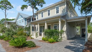 A two-story house with a porch, surrounded by landscaped garden beds and trees. - Spacious, golf cart included-pet friendly, short stroll to beach (Santa Rosa Beach)