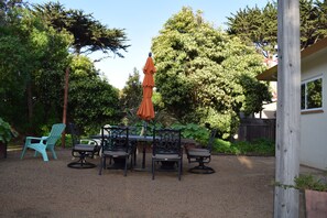 An outdoor patio with a table and chairs, surrounded by trees and a wooden fence. - Birdies, Beaches and Butterflies in Pacific Grove! Pet Friendly-Premier location (Pacific Grove)