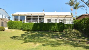 Un bâtiment à deux étages, doté d’un toit plat, de grandes fenêtres et d’un espace extérieur aménagé avec des sièges.