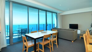 Et moderne hotelværelse med balkon, spiseplads, sofa og tv.
