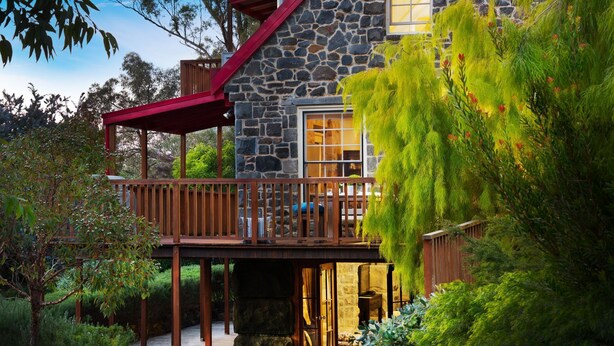 A stone house with a wooden deck and a covered area.