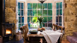 A cozy dining area with a stone fireplace, wooden table, and chairs.