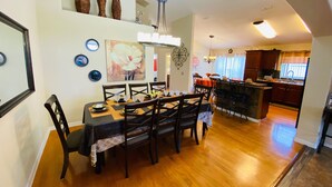 A dining area with a wooden table and chairs, a chandelier, and a painting on the wall.