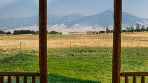 Un belvédère en bois offrant une vue sur un champ verdoyant et, au loin, sur des montagnes.