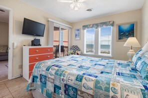 A bedroom with a bed, a TV, a dresser, and a window with blinds.
