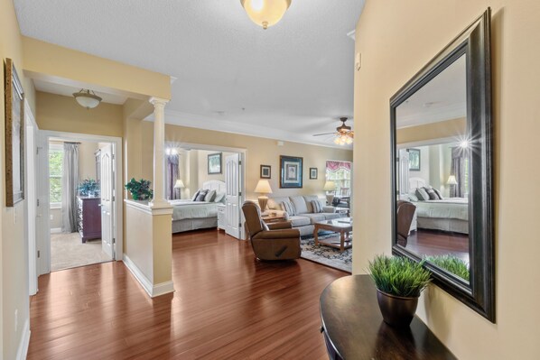 A spacious living room with hardwood flooring, a large mirror, and a comfortable seating area.