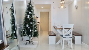 A modern dining area with a Christmas tree, white furniture, and a wooden bench. - Modern Country Family Suite w/ Stunning Taal View (Tagaytay)