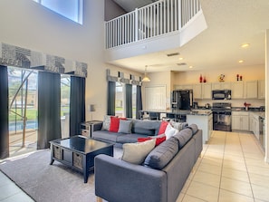 Spacious living area with a mezzanine level, featuring a sectional sofa, coffee table, and kitchen with modern appliances.