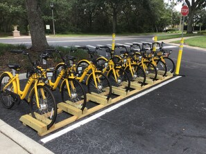 A row of yellow bicycles parked on wooden stands in a designated bike parking area. - ALWAYS FREE POOL HEAT - 3 miles to Disney, Emerald Island Resort - GAME ROOM (Kissimmee)