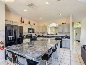 Enjoy cooking in this well-equipped kitchen with a large island, bar stools, and modern appliances.