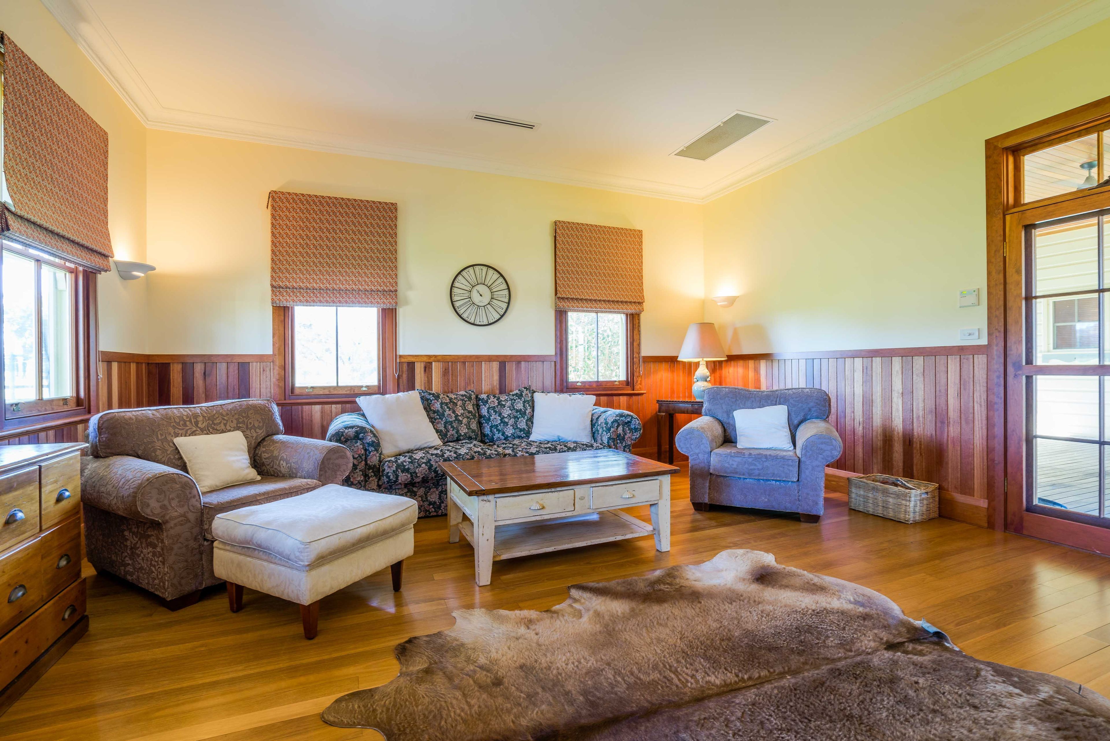 A cozy living room with a wooden floor, a sofa set, a coffee table, and a rug.