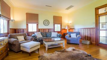 A cozy living room with a wooden floor, a sofa set, a coffee table, and a rug.