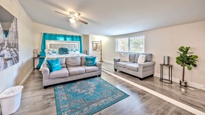 A spacious living room with a grey sofa, a blue patterned rug, and a ceiling fan. - Lovely home -5 min from the strip (Las Vegas)