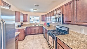 A modern kitchen with granite countertops, stainless steel appliances, and wooden cabinets. - Lovely home -5 min from the strip (Las Vegas)