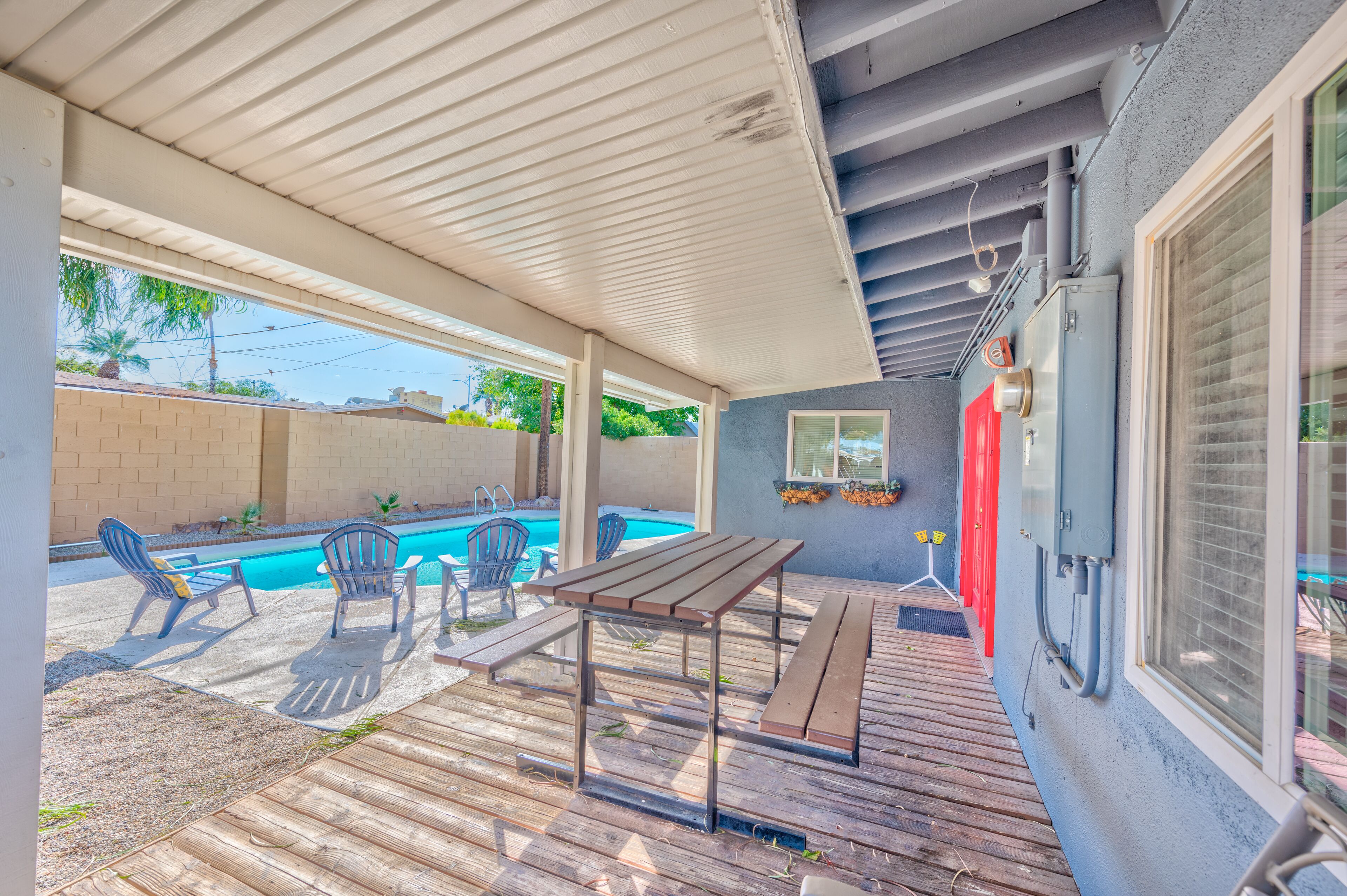 A covered patio with a pool, outdoor furniture, and a wooden deck.