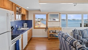 A kitchen with wooden cabinets, a blue tiled backsplash, and a view of the sea.