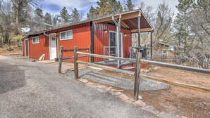 Ein rotes Gebäude aus Metall mit Veranda, Satellitenschüssel und Kiesweg.