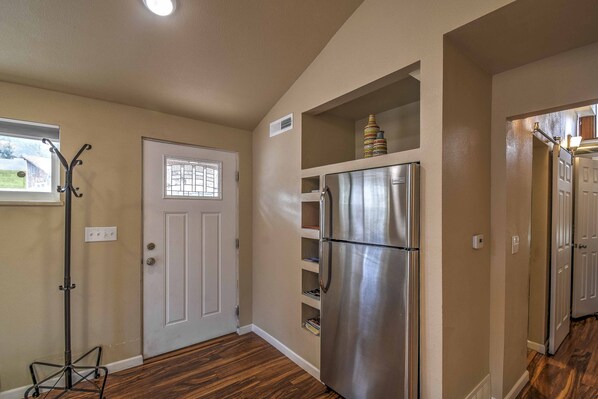 A kitchen with a stainless steel refrigerator, wooden flooring, and a white door with a window.