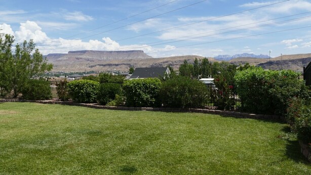 A grassy backyard with a view of mountains and a small house. - PRIVATE POOL 34'x18', 25 Minutes to Zion,  Playset for Kids, 7 bdrm, sleeps 32 (Hurricane)