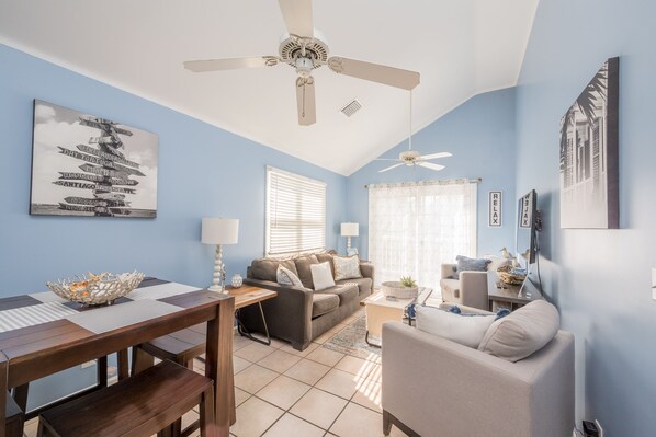A living room with a ceiling fan, a dining table with chairs, a sofa, and a coffee table. - Blue Heaven at The Truman Annex in Key West (Key West)