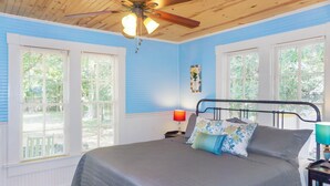 Un dormitorio con cama, mesita de noche, lámpara y ventilador de techo.