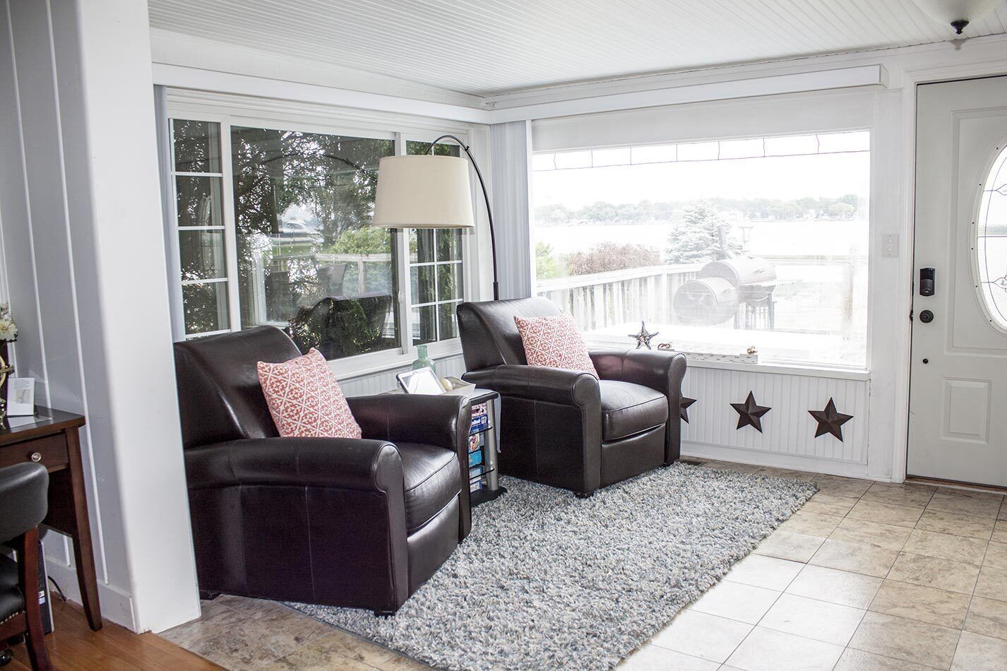 A cozy living room with two leather armchairs, a large window, and a door with star decorations.