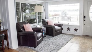 Un salon chaleureux avec deux fauteuils en cuir, une grande fenêtre et une porte décorée de motifs en forme d’étoiles.