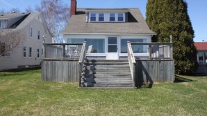 Une maison à deux étages avec une terrasse à l’avant et un escalier menant à l’entrée.