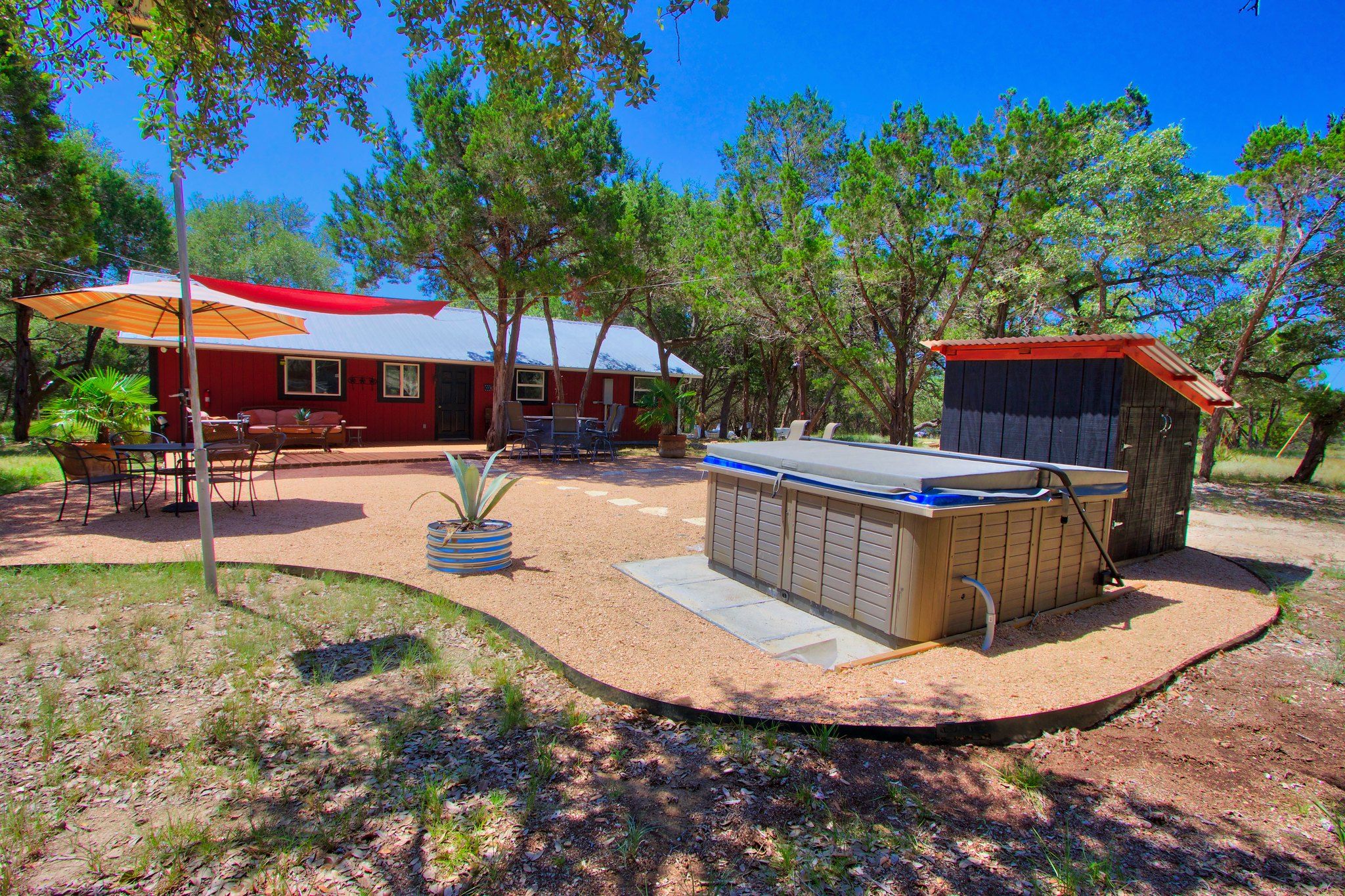 A red house with a patio, outdoor seating, and a hot tub.