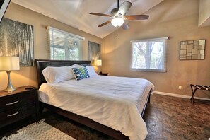 A bedroom with a bed, two bedside tables, a ceiling fan, and two windows with blinds. - Secluded Cabin with ALL the amenities (Wimberley)