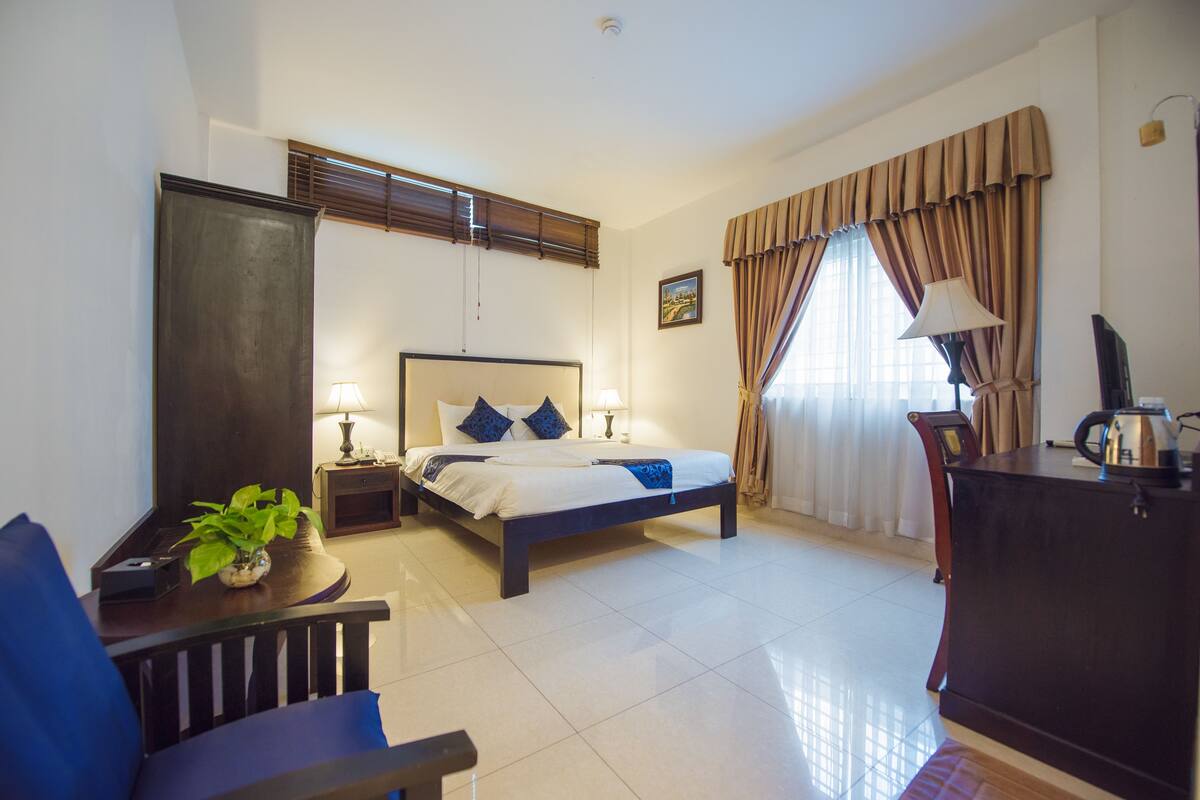 Una habitación de hotel con cama, mesitas de noche, escritorio, silla y televisor.