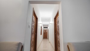 Un couloir avec deux portes en bois, un luminaire et un sol carrelé.