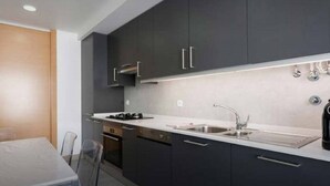 A modern kitchen with dark cabinetry, a stainless steel sink, and a white countertop.