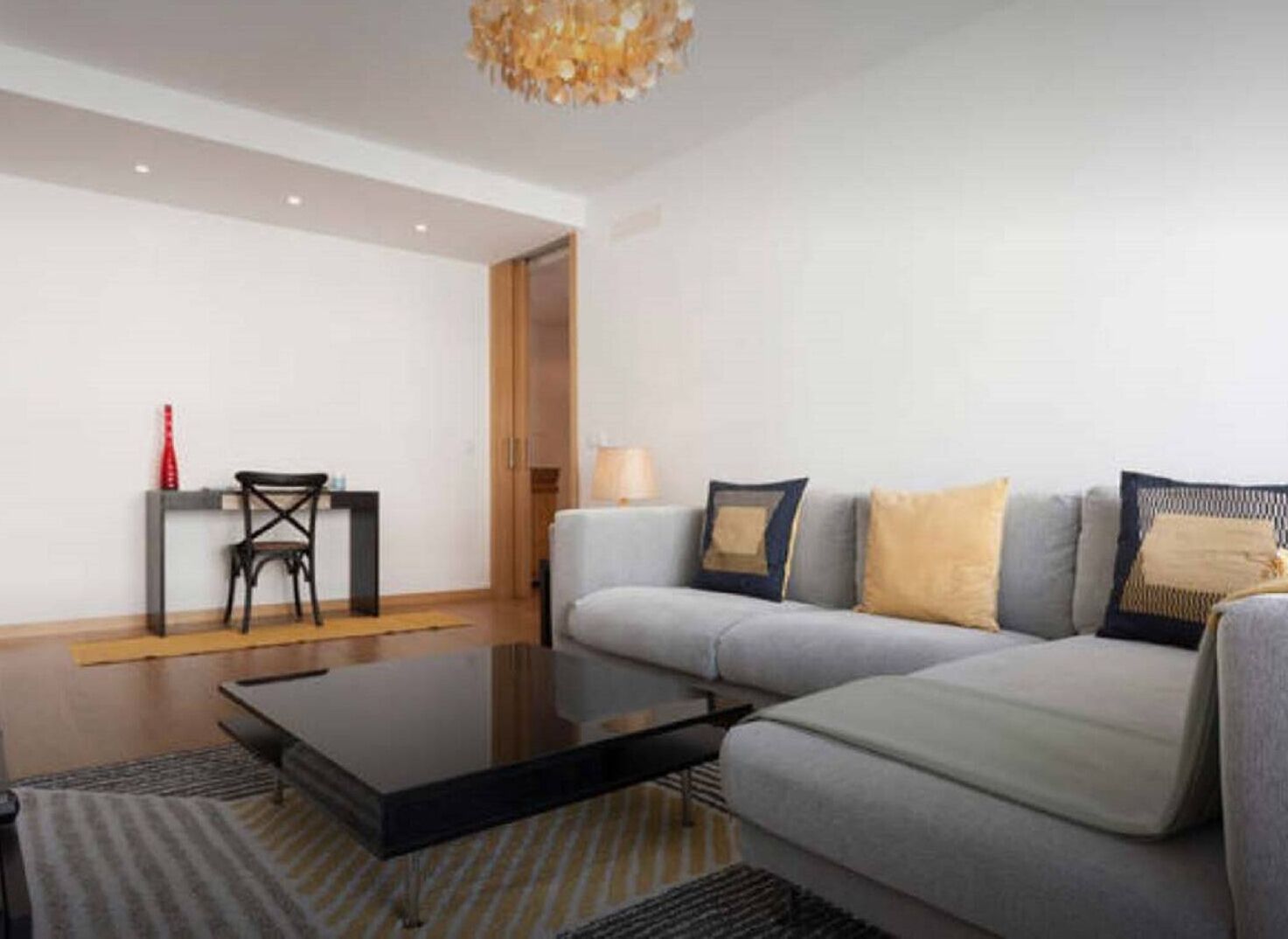 A modern living room with a grey sofa, a coffee table, a small side table, and a chair.