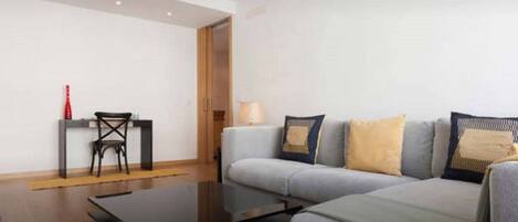 A modern living room with a grey sofa, a coffee table, a small side table, and a chair.
