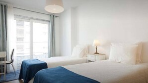 A hotel room with two beds, a desk, and a chair.