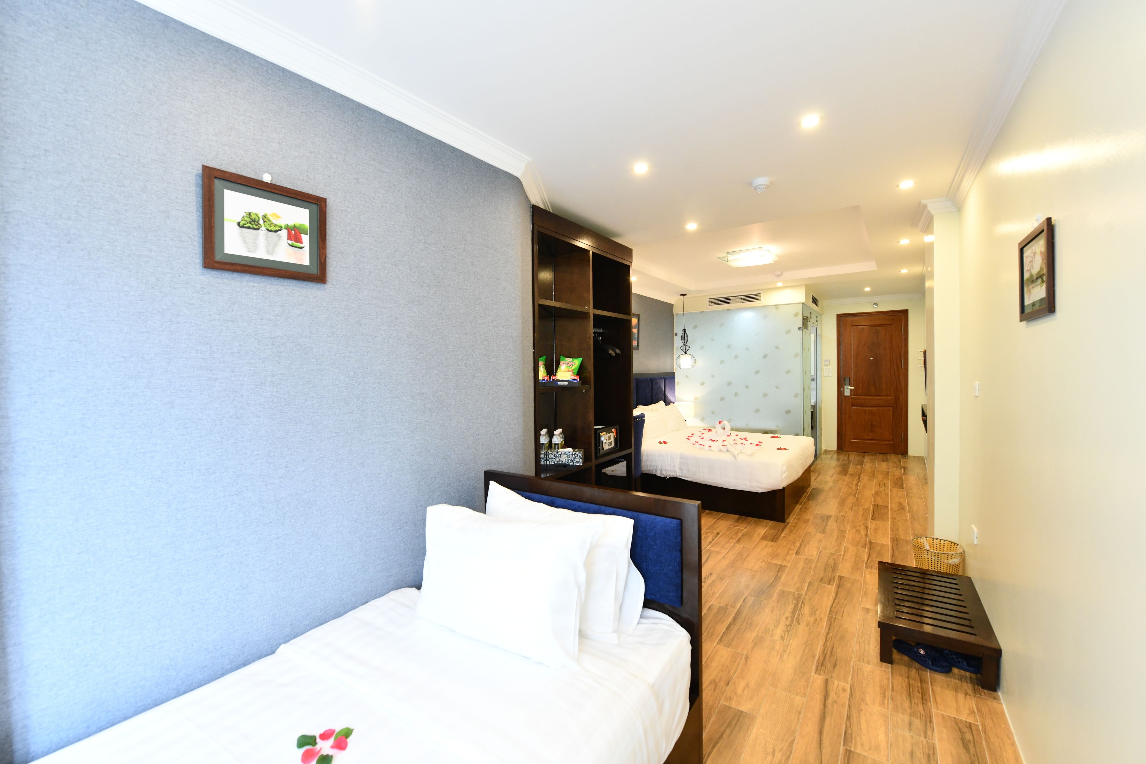 Une chambre d’hôtel avec deux lits, une armoire et un petit coin salon.