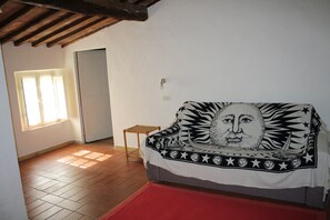 Relax in this inviting space with a sofa and stool, surrounded by a window and a tiled floor.