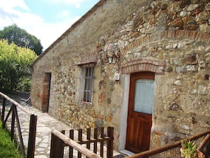 Traditional stone building with a wooden door and metal bars on a stone pathway.