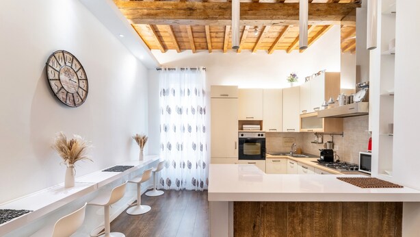 A modern kitchen with white countertops, wooden beams, and a large island.