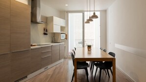 A modern kitchen with wooden cabinets, a dining table with chairs, and pendant lights.