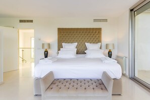A hotel room with a large bed, two bedside tables, a headboard, and a seating area with a cushioned bench.