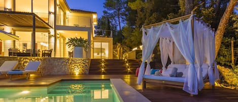Un edificio moderno de dos pisos con piscina y terraza de madera.
