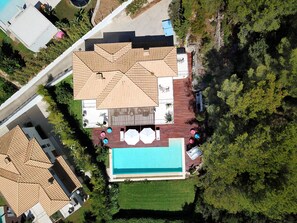 Vista aérea de uma propriedade residencial com piscina, área de estar externa e um alpendre coberto.